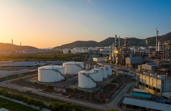 an aerial view of a large oil refinery with mountains in the background at sunset .