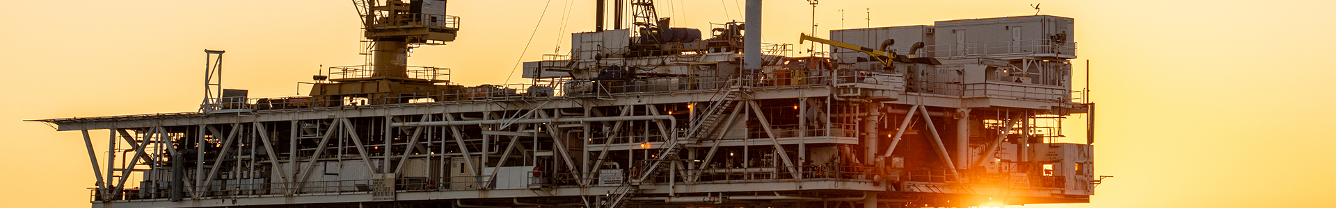 the sun is setting behind a large oil rig