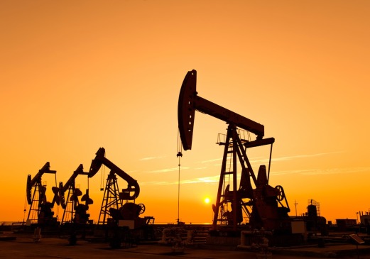 two oil pumps are silhouetted against a sunset sky