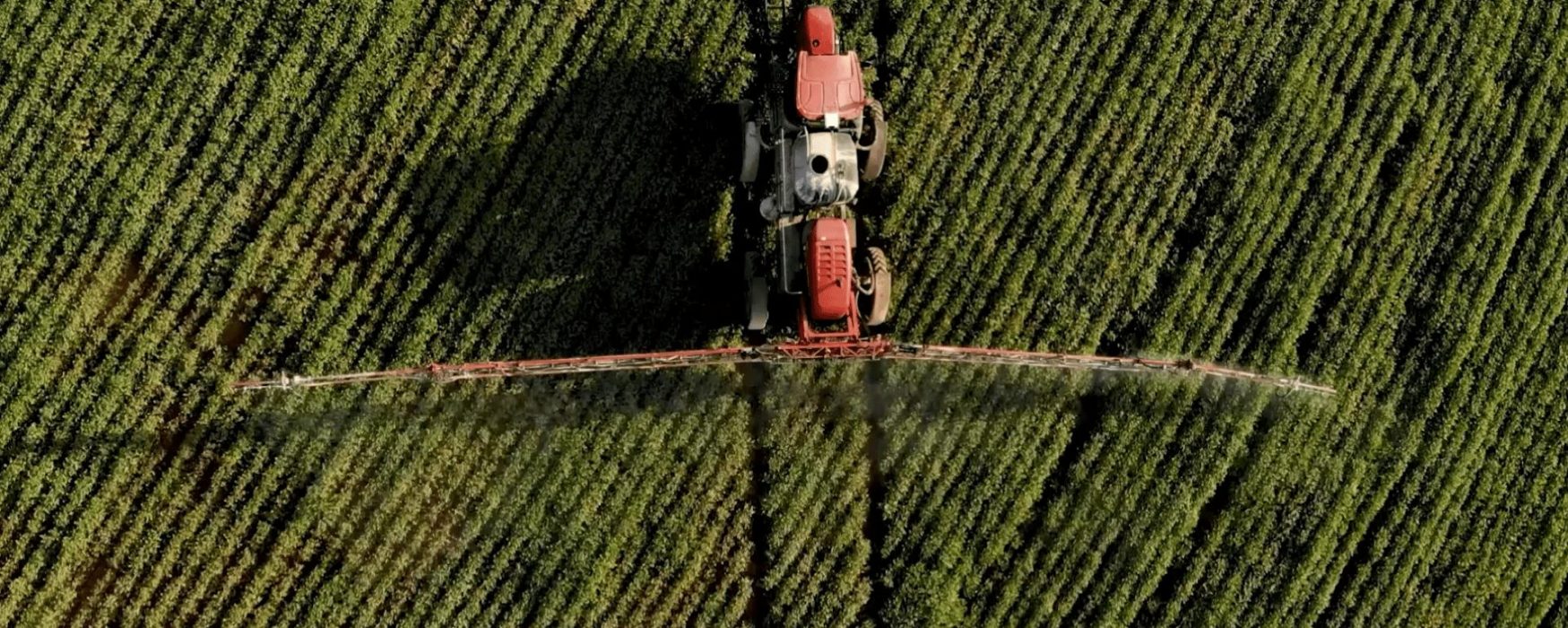 an aerial view of a tractor spraying a corn field